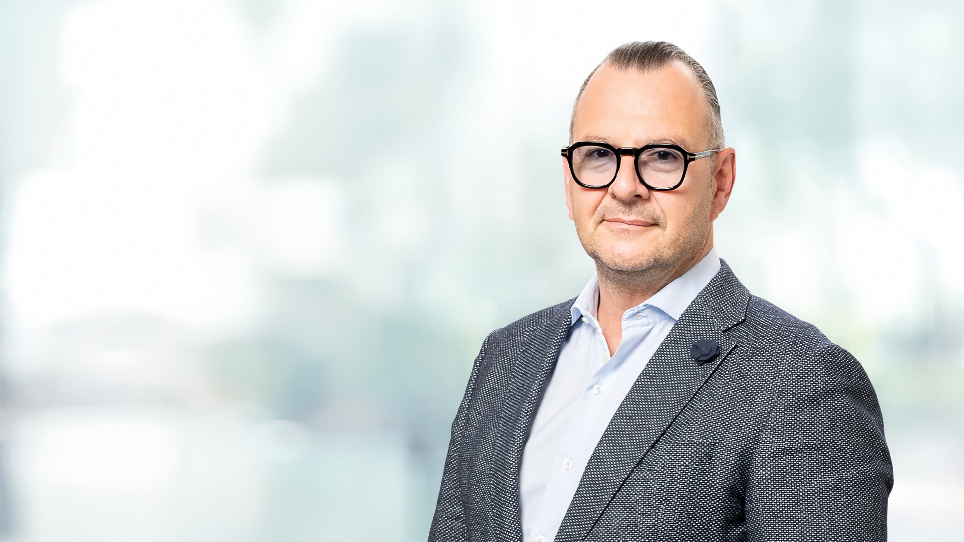 Ing. Paul Eichberger in der rechten Bildhälfte, Brustbild mit dunkler Brille und grauem Sakko; die linke Bildhälfte ist heller, unscharfer Hintergrund.